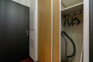 A hallway with a dark door, a wooden door, and a coat rack with hangers. - Holiday Apartment "Valfréjus" in Valfréjus (Modane)