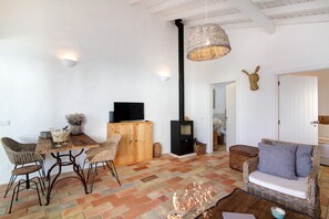 A cozy living area with a fireplace, wicker furniture, and a television.