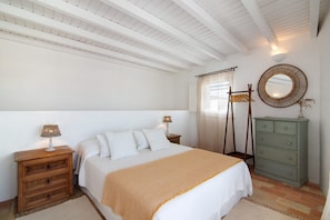 A bedroom with a bed, wooden nightstand, dresser, and a mirror.