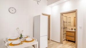 A modern kitchen with a white refrigerator, a dining table set with plates and cutlery, and a clock on the wall. - Apartment 'Casa De La Esperanza' with Wi-Fi and Air Conditioning (Alicante (Alacant))
