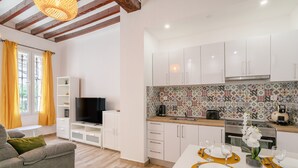 A modern kitchen with white cabinets, a tiled backsplash, and a dining area set for four with a white table and orange placemats. - Apartment 'Casa De La Esperanza' with Wi-Fi and Air Conditioning (Alicante (Alacant))