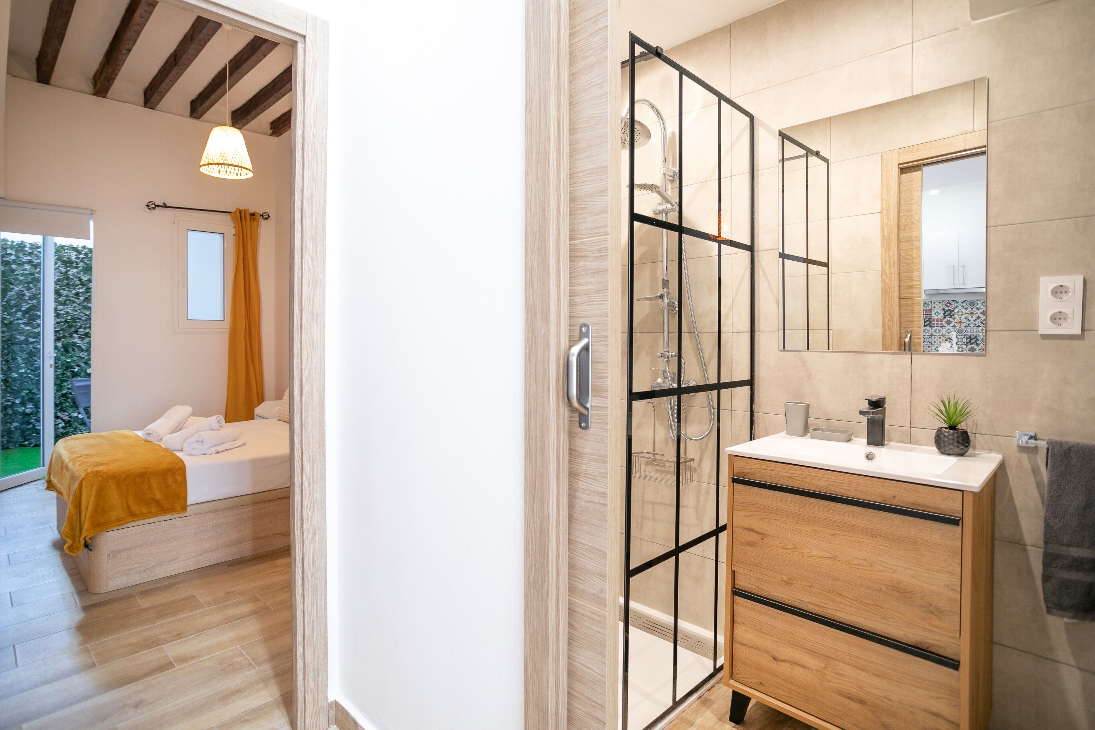 Een moderne badkamer met een douche, een spiegel en een houten wastafelmeubel.