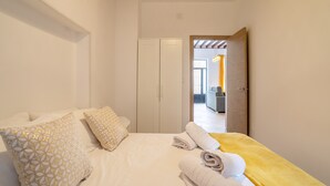 A bedroom with a bed, pillows, a yellow towel, and a wardrobe. - Apartment 'Casa De La Esperanza' with Wi-Fi and Air Conditioning (Alicante (Alacant))