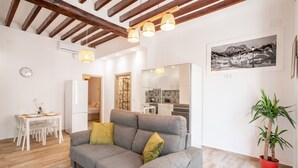 A living room with a grey sofa, a dining table with chairs, a kitchen in the background, and a potted plant. - Apartment 'Casa De La Esperanza' with Wi-Fi and Air Conditioning (Alicante (Alacant))