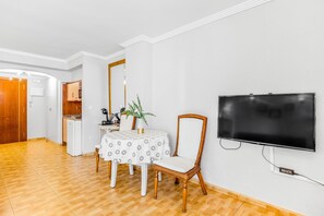 Une pièce comprenant une table à manger, des chaises, un téléviseur et un coin cuisine.