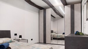 Un dormitorio con cama, mesita de noche, espejo y cómoda.