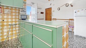 Una cocina con una isla verde, un microondas y un refrigerador.