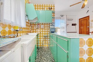Una cocina con salpicadero de azulejos, ventilador de techo y puerta de madera.