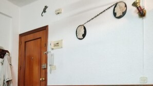 Una habitación con un sofá verde, una puerta de madera, un interruptor de luz en la pared y una pequeña decoración de pared.