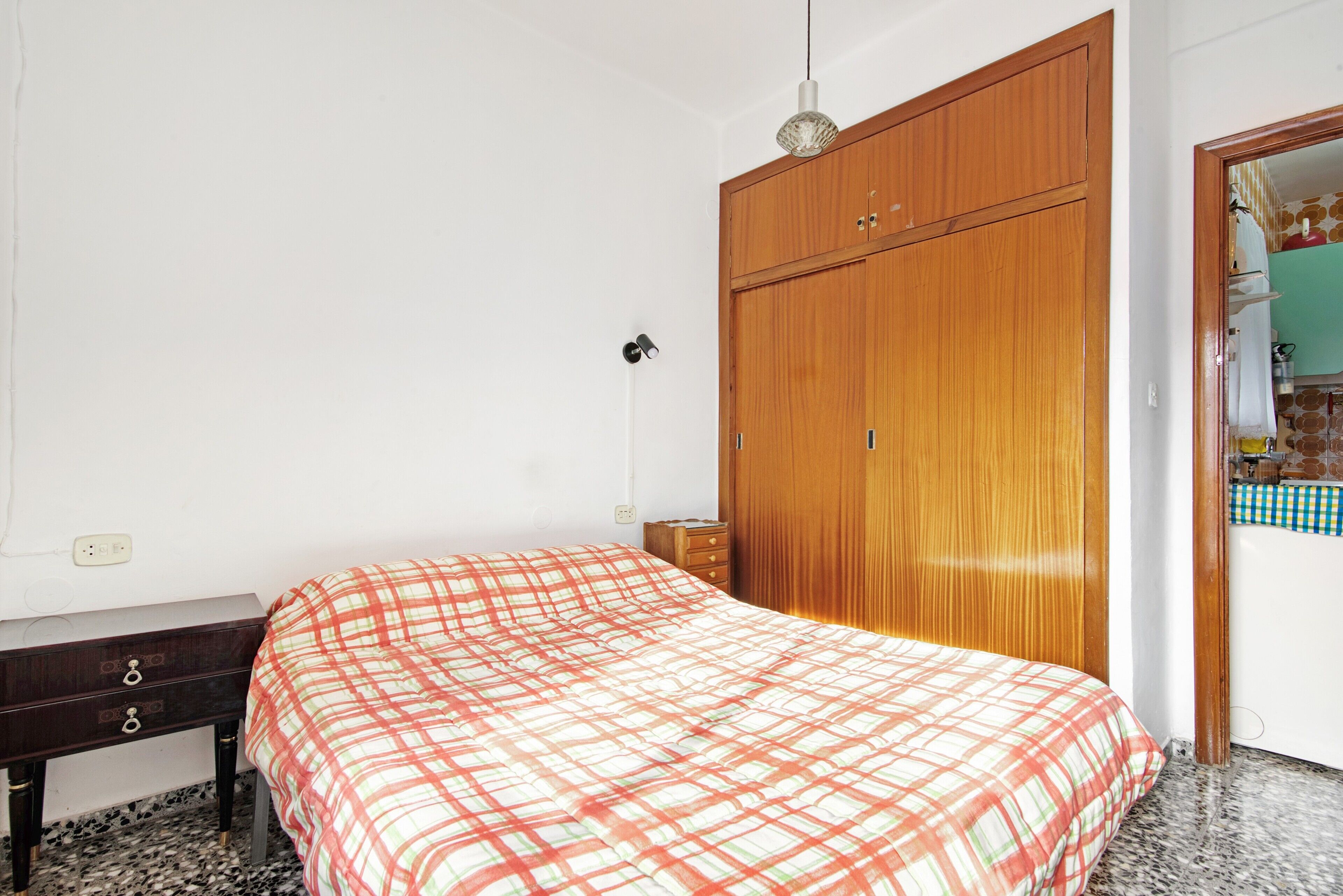 Un dormitorio con una cama, un armario de madera, una mesita de noche y un espejo.
