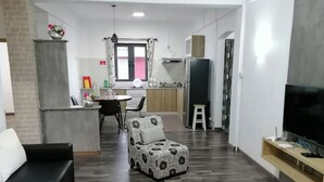 A modern living room with a black sofa, a patterned ottoman, and a flat-screen TV. - Bobato Appartement D (Curepipe)