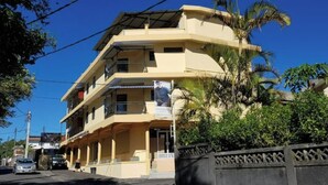 A multi-story building with balconies, a gated entrance, and a clear blue sky. - Bobato Appartement D (Curepipe)