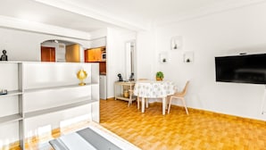 Un espacio habitable moderno con comedor, cocina y televisor montado en la pared.