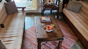 A cozy living area with a sofa, a wooden coffee table with a bowl of fruit, a patterned cushion, and a wall-mounted hat. - Holiday Home 'Traditional Farmhouse' with Mountain View, Private Terrace and Private Garden (Lefkada)
