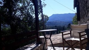 A stone patio with a table and chairs, overlooking a mountainous landscape. - Holiday Home 'Traditional Farmhouse' with Mountain View, Private Terrace and Private Garden (Lefkada)
