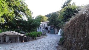 A cobblestone street leading to a stone building with a tiled roof, surrounded by greenery and a stone wall. - Holiday Home 'Traditional Farmhouse' with Mountain View, Private Terrace and Private Garden (Lefkada)
