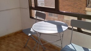 Una habitación con ventana, una mesa redonda, dos sillas y una estantería de metal.
