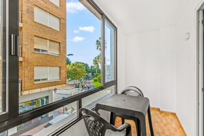 A balcony with a view of a street, a table, and chairs.