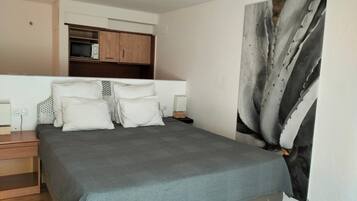 Un dormitorio con cama, mesitas de noche, un armario y un cuadro abstracto grande en la pared.