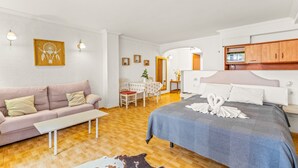 A bedroom with a bed, a sofa, a desk, and a mirror.