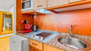 A compact kitchen with a microwave, toaster, and sink.