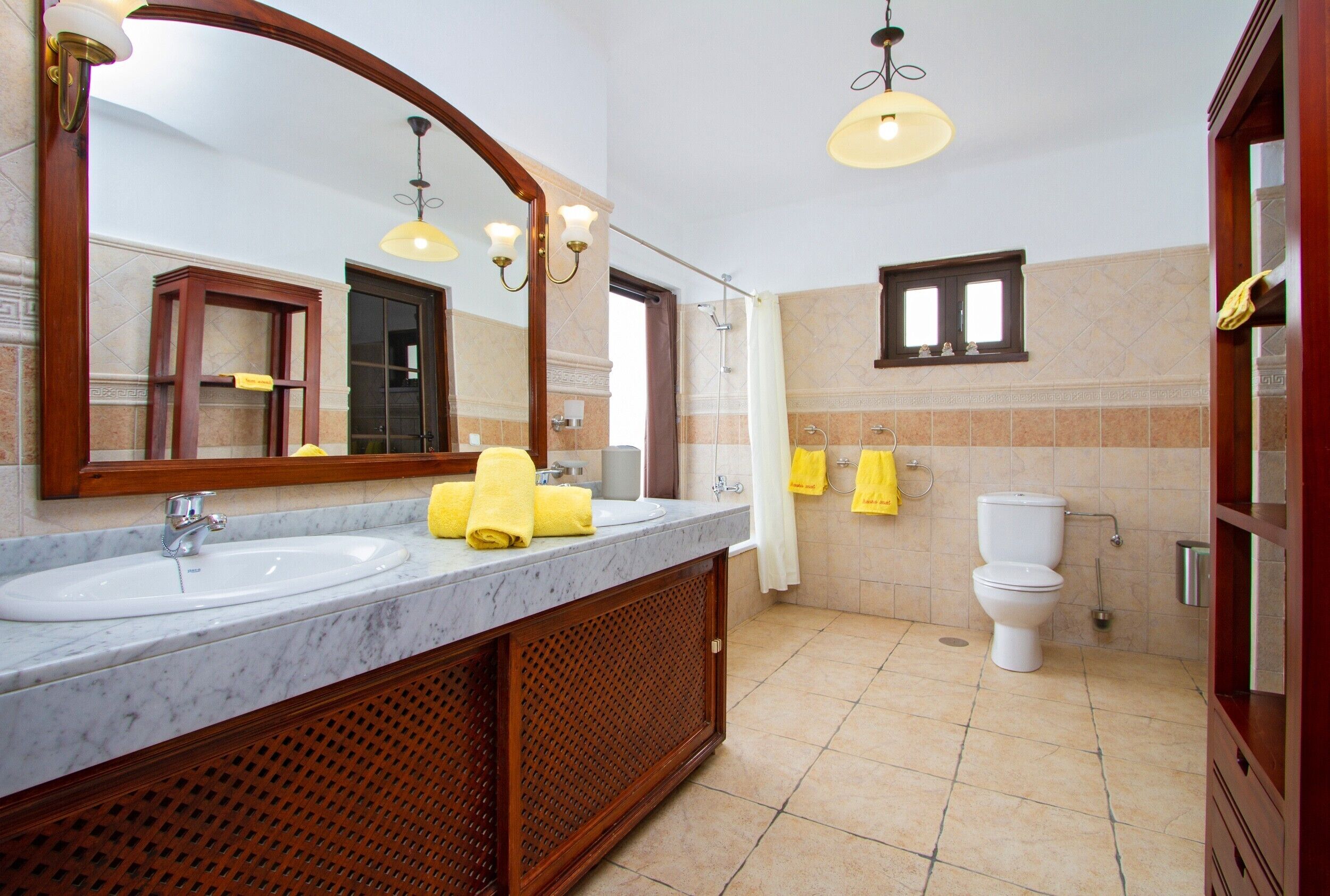 Un baño con dos lavamanos, un espejo, una ducha y un inodoro.