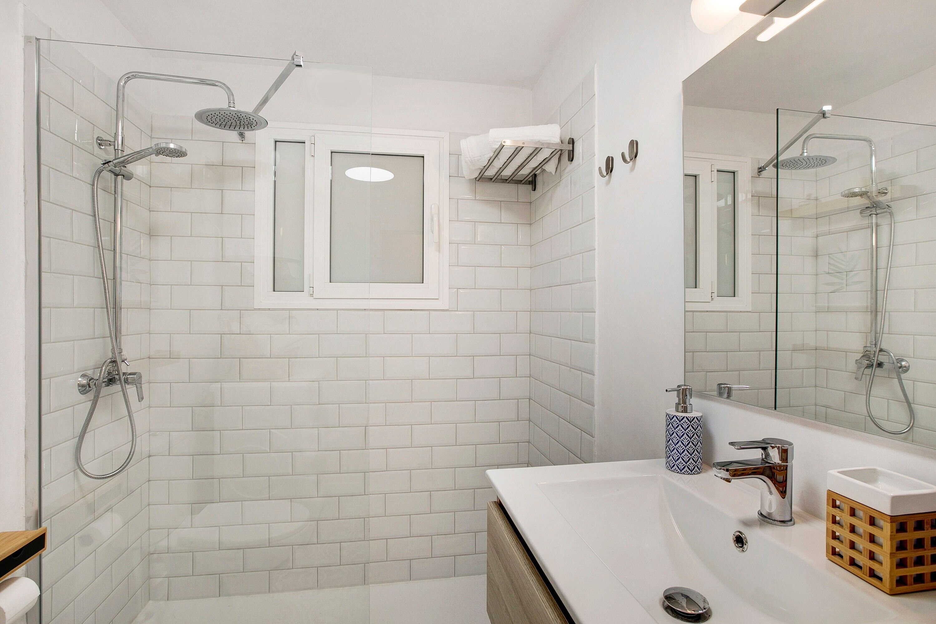A bathroom with a glass shower enclosure, a white sink, and a mirror.