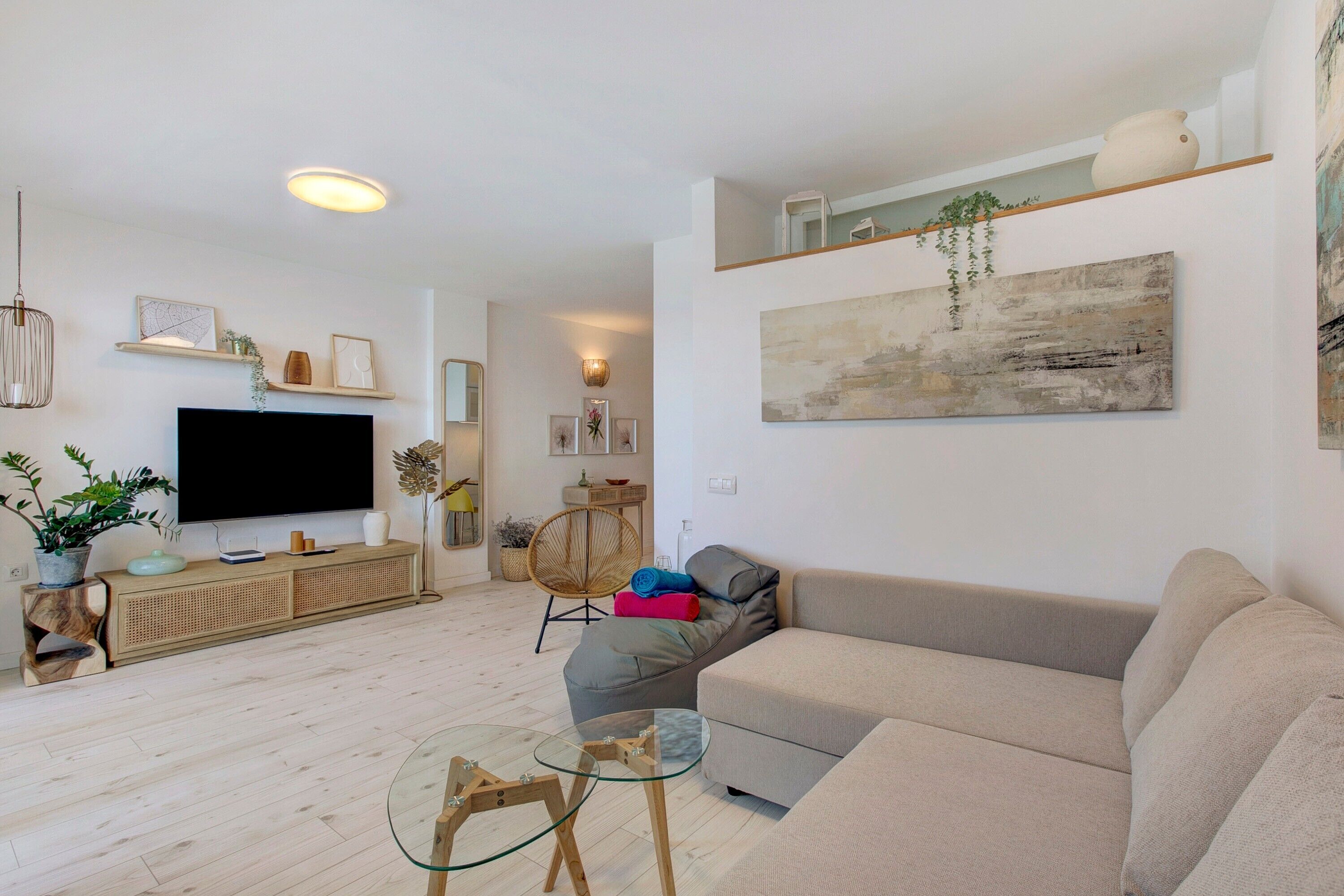 Una sala de estar con un sofá, una mesa de centro de cristal, un televisor y un cuadro en la pared.