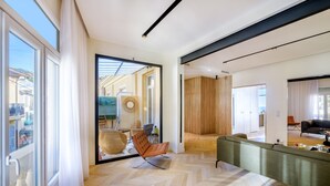 A modern interior with a herringbone floor, a green sofa, a wooden door, and a view through a glass door. - Holiday Apartment 'De luxe Bluesky' with Terrace, Balcony & Wi-Fi (Beausoleil)