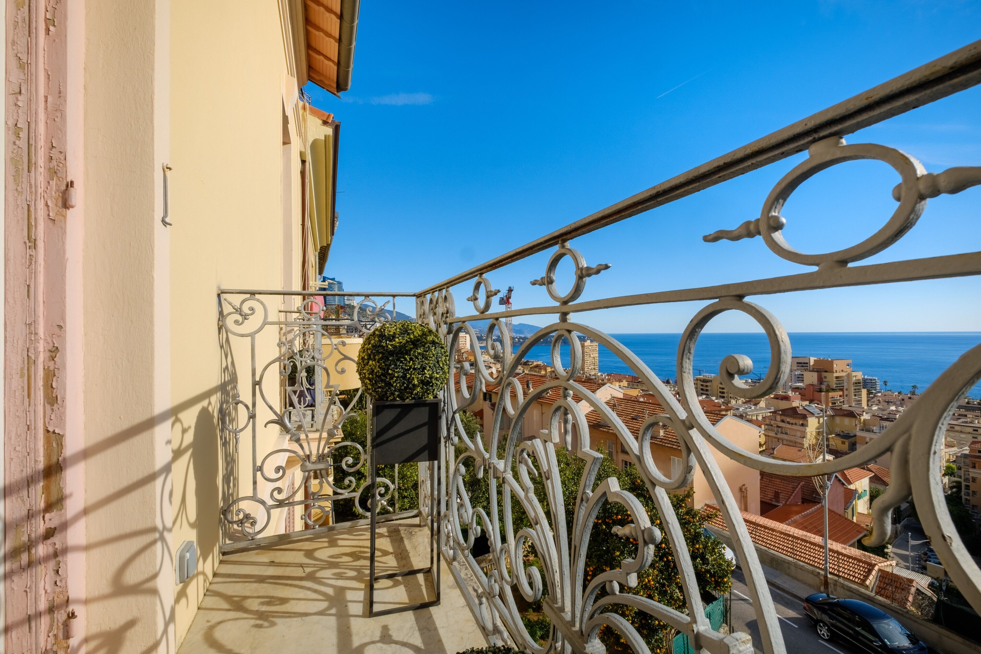 Un balcone con ringhiere in metallo decorate, affacciato su una città costiera.
