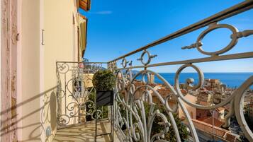 Un balcone con ringhiere in metallo decorate, affacciato su una città costiera.