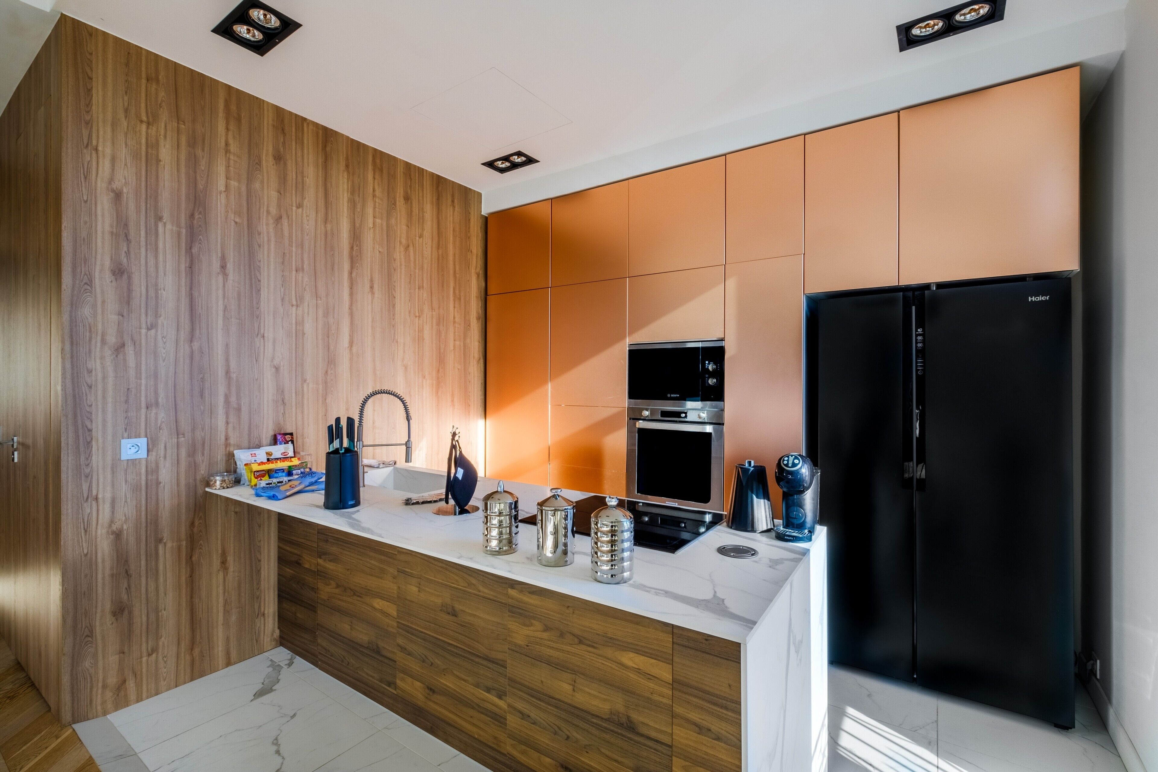 Una cucina moderna con mobili in legno, un frigorifero nero ed elettrodomestici in acciaio inossidabile.