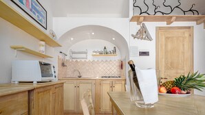 Een keuken met houten kastjes, een magnetron, een spoelbak en een fruitschaal op het aanrecht.