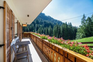 Ein Balkon mit Holzbalkonen, einem Tisch und Stühlen.