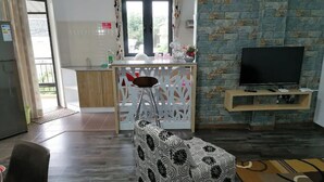 Una sala de estar con sofá, televisión, comedor y cocina.