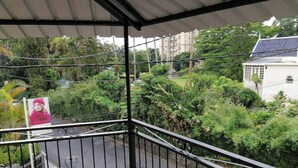 Un balcón con vista a un jardín exuberante y edificios residenciales.