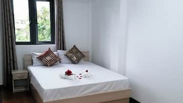 Une chambre à coucher avec un lit, une table de chevet, une fenêtre avec des rideaux et une vue sur la verdure à l’extérieur.