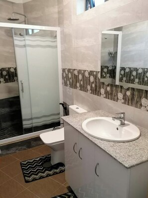 Une salle de bain moderne équipée d’une douche, de toilettes et d’un lavabo.