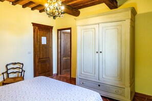 A bedroom with a bed, wooden wardrobe, and a chair.
