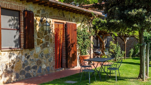 A stone building with a brick roof, a wooden door, and a window with shutters. There is a table and chairs outside. - Apartment 'Grillo' with Shared Pool, Wi-Fi and Air Conditioning (Montiano)