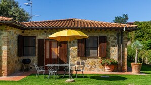 A stone building with a tiled roof, a patio with a table and chairs, and a yellow umbrella. - Apartment 'Formica' with Shared Pool, Wi-Fi and Air Conditioning (Montiano)
