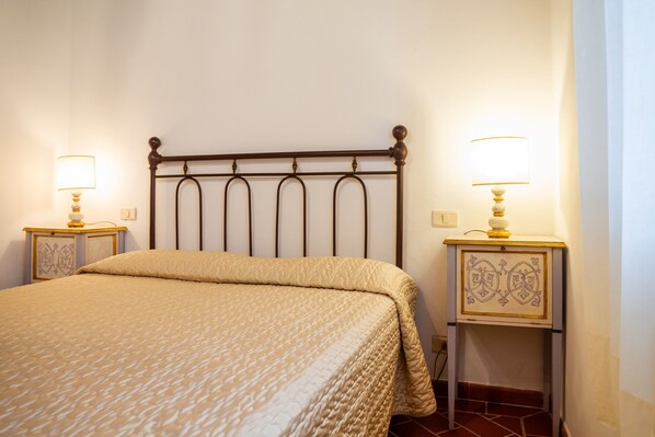 Un lit bien fait, recouvert d’une couvre-lit à motifs, deux tables de chevet avec des lampes et un panneau décoratif au mur.