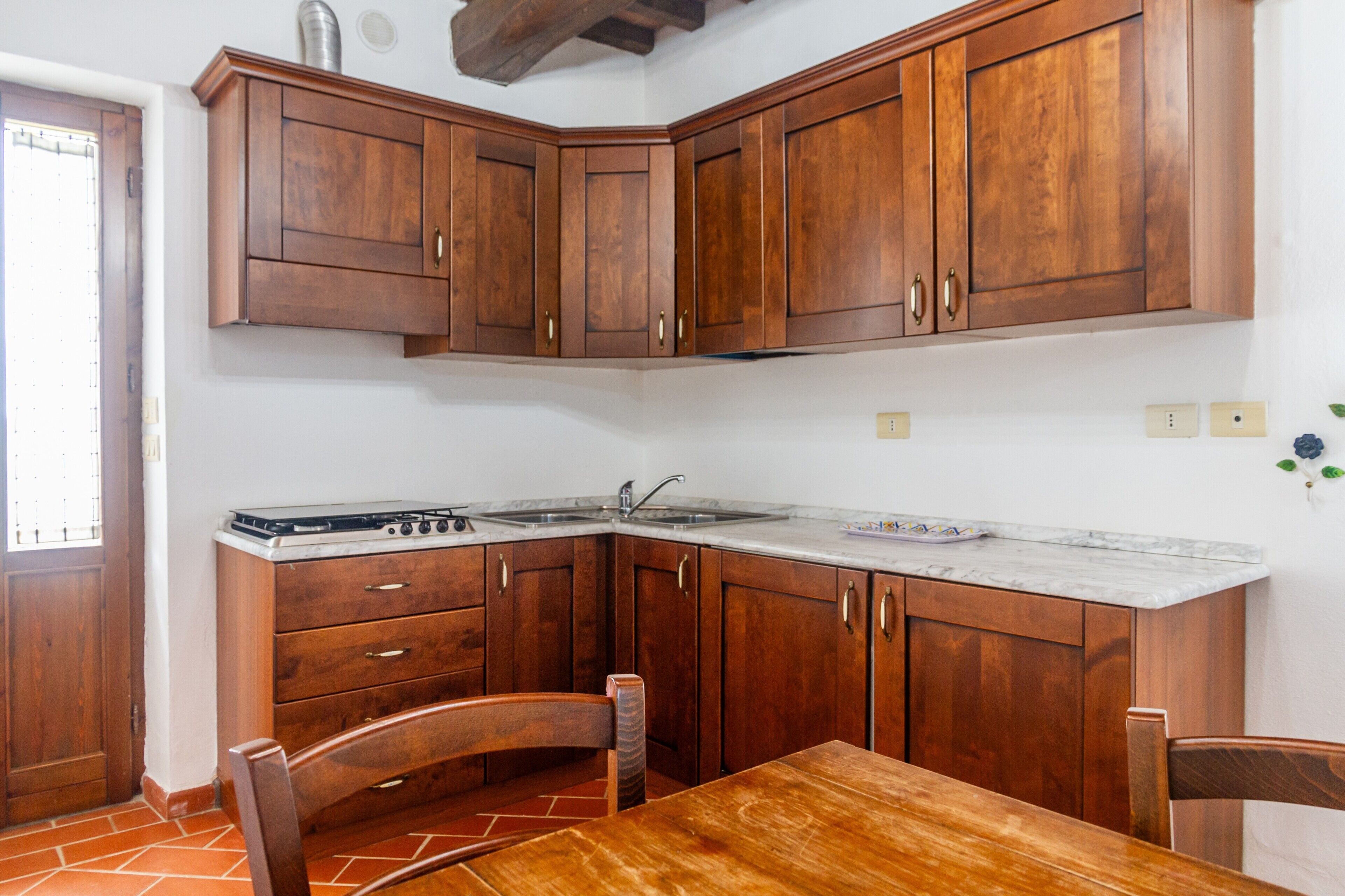 A kitchen with wooden cabinets, a stove, and a dining table.