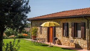 A stone building with a tiled roof, a patio with a table and chairs, and a yellow umbrella. - Apartment 'Tartaruga' with Shared Pool, Wi-Fi and Air Conditioning (Montiano)