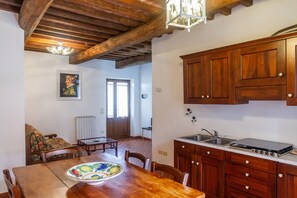 A kitchen with wooden cabinets, a stove, and a dining area with a table and chairs. - Apartment 'Tartaruga' with Shared Pool, Wi-Fi and Air Conditioning (Montiano)