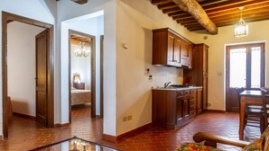 A spacious living area with a sofa, a glass coffee table, wooden cabinets, and a kitchen area with a sink and countertop. - Apartment 'Tartaruga' with Shared Pool, Wi-Fi and Air Conditioning (Montiano)