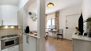 A kitchen with a gas stove, oven, and microwave, a dining area with a table and chairs, and a white door. - Holiday Home 'Mdc - Muralhas Da Cidade' with Wi-Fi (Lagos)