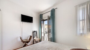 A bedroom with a bed, a chair, a television, and a window with curtains. - Holiday Home 'Mdc - Muralhas Da Cidade' with Wi-Fi (Lagos)
