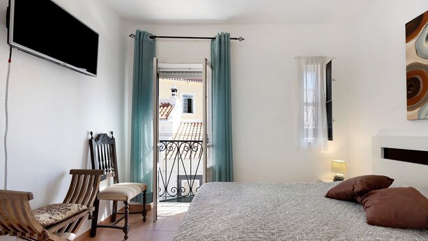 A bedroom with a bed, a chair, a desk, a TV, and a balcony view. - Holiday Home 'Mdc - Muralhas Da Cidade' with Wi-Fi (Lagos)