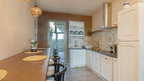Eine Küche mit einem Holztisch, weißen Schränken und einem weißen Kühlschrank.